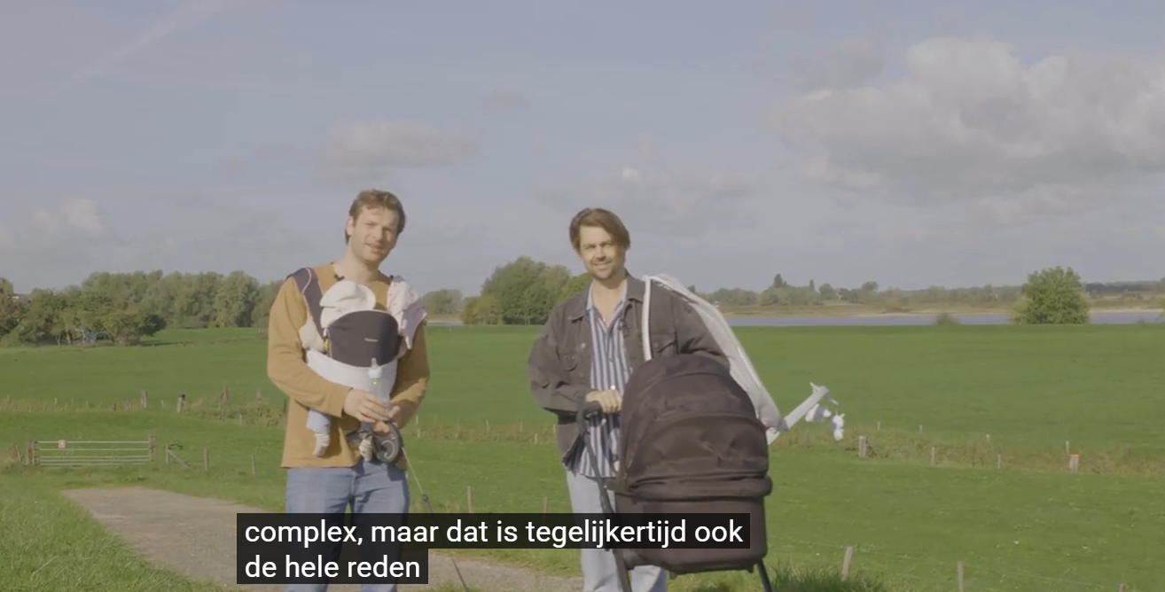 Twee vaders in een weiland, een met een baby in de draagzak en een met een kinderwagen. Still uit de film.